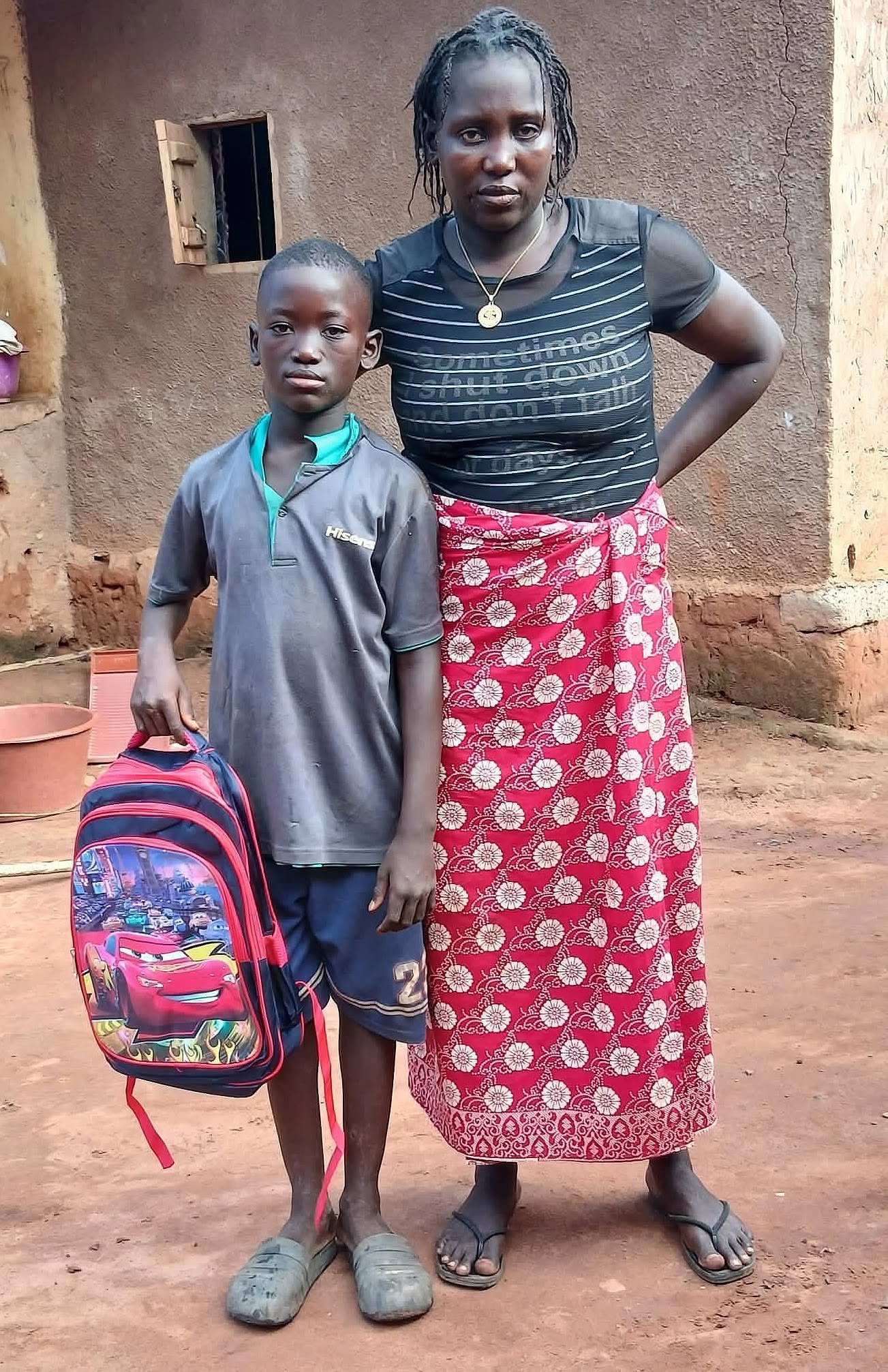 Escolar con mochila roja junto a una adulta en Diassia