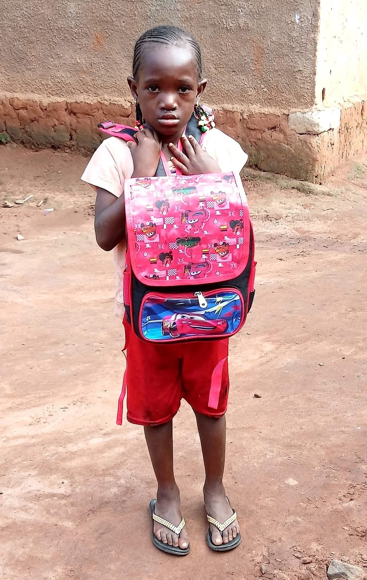 Escolar mostrando una mochila rosa y roja