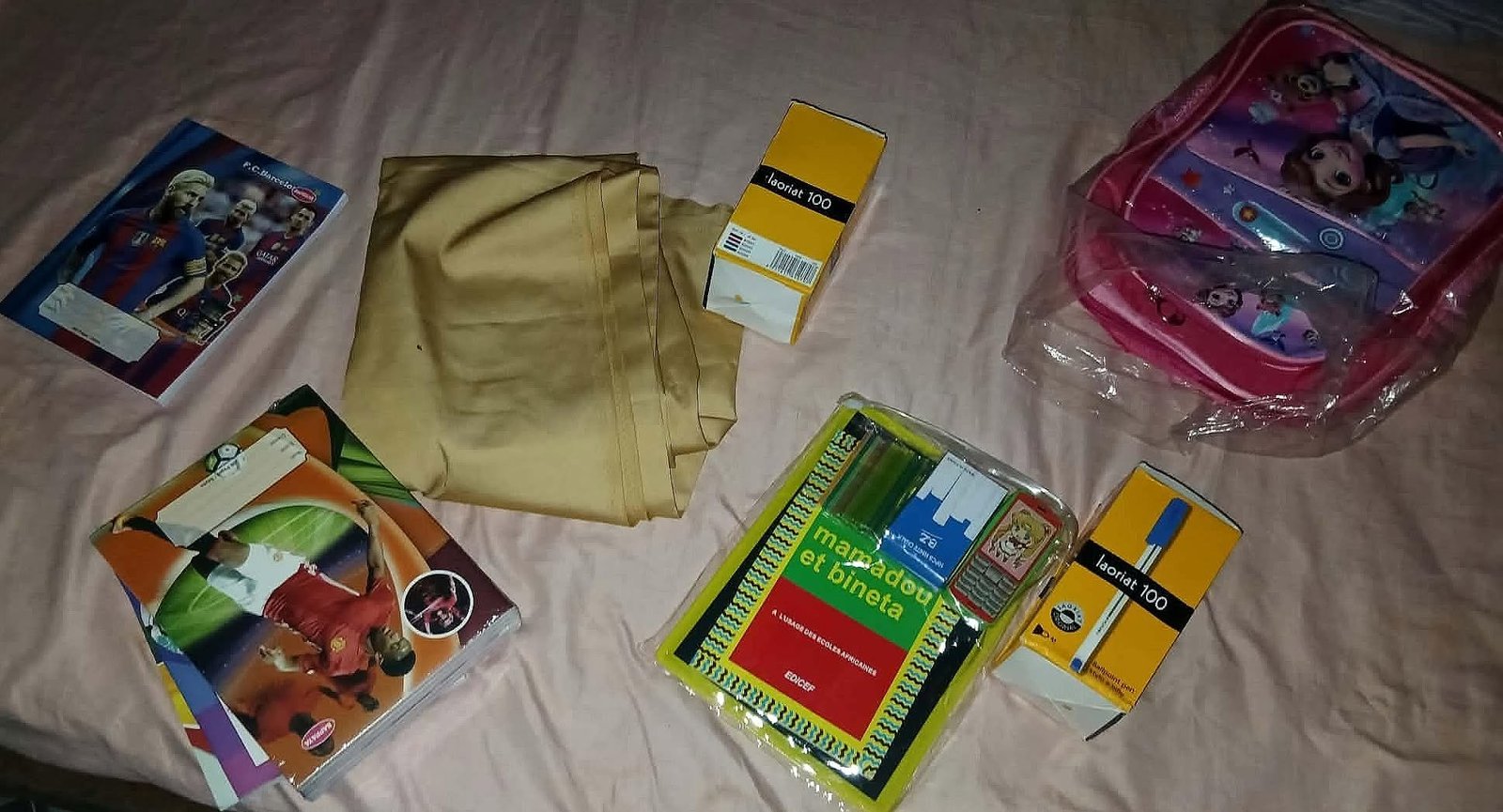 Cuadernos, bolígrafos y otros útiles escolares junto a una mochila