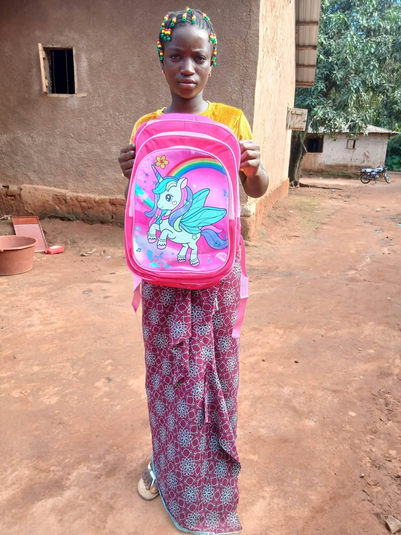 Escolar mostrando una mochila rosa al inicio del curso